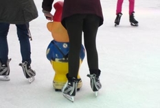Öffentliche Eisbahn mit Schlittschuhläufern im Winter